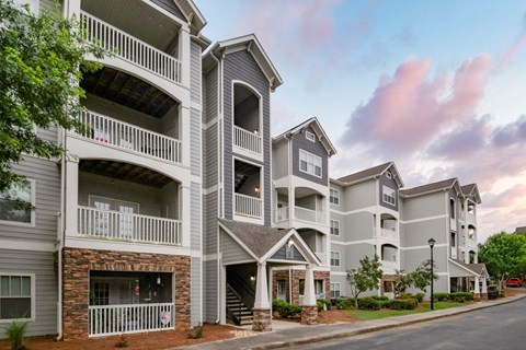 Apartment building with balconies and a cloudy sky.