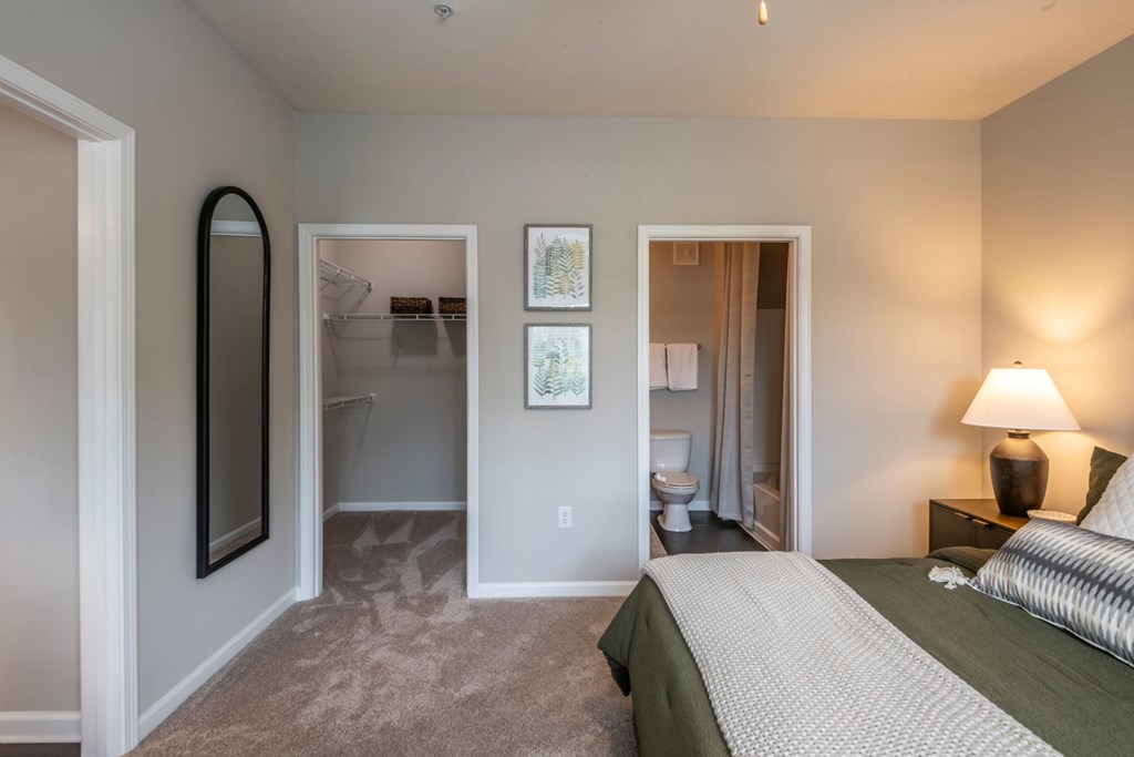 A bedroom with a bed, dresser, and mirror at Ansley at Town Center Apartments, Georgia