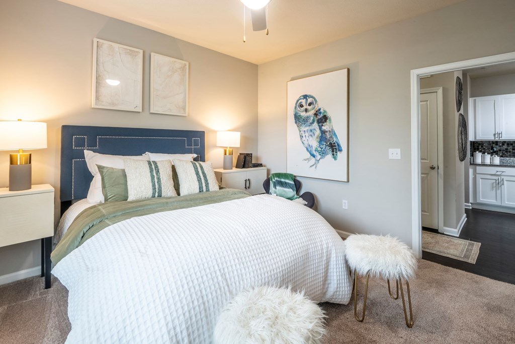 A bedroom with a large bed and a painting of an owl on the wall at Ansley at Town Center Apartments, Evans, Georgia