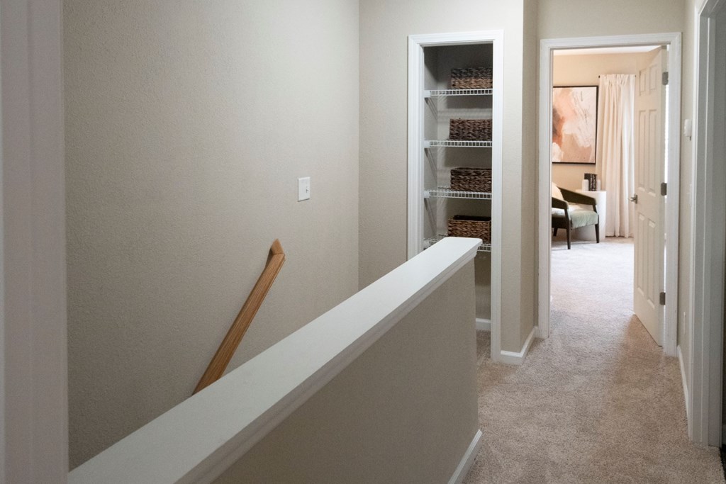 A hallway with a white wall and a white bench at Ansley at Town Center Apartments, Evans, GA 30809