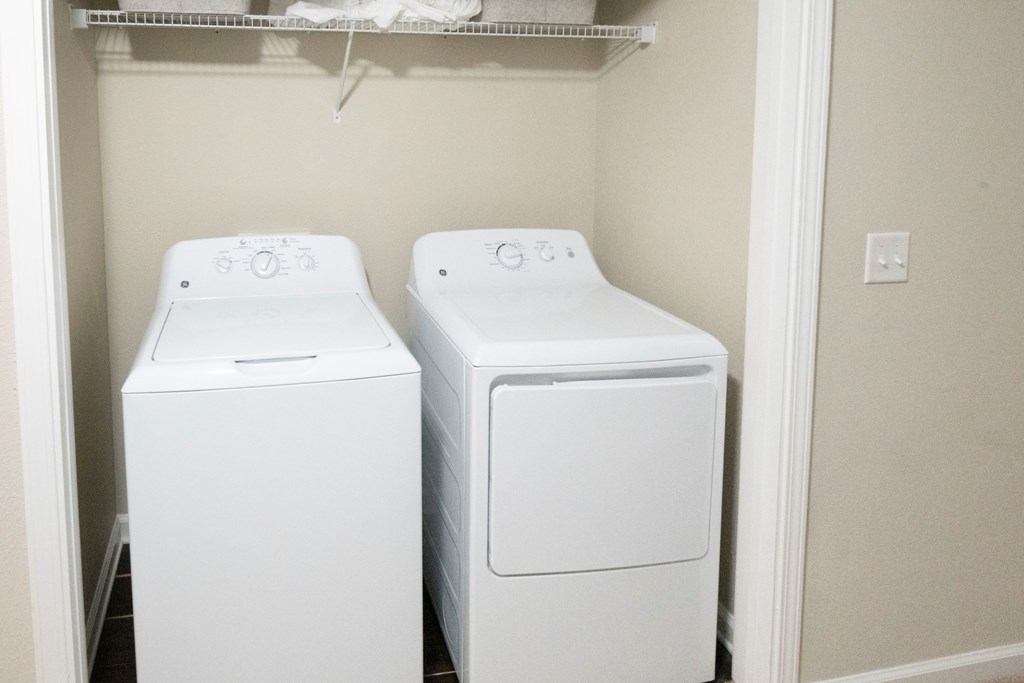Two white front loading washing machines in a small laundry room at Ansley at Town Center Apartments, Georgia, 30809