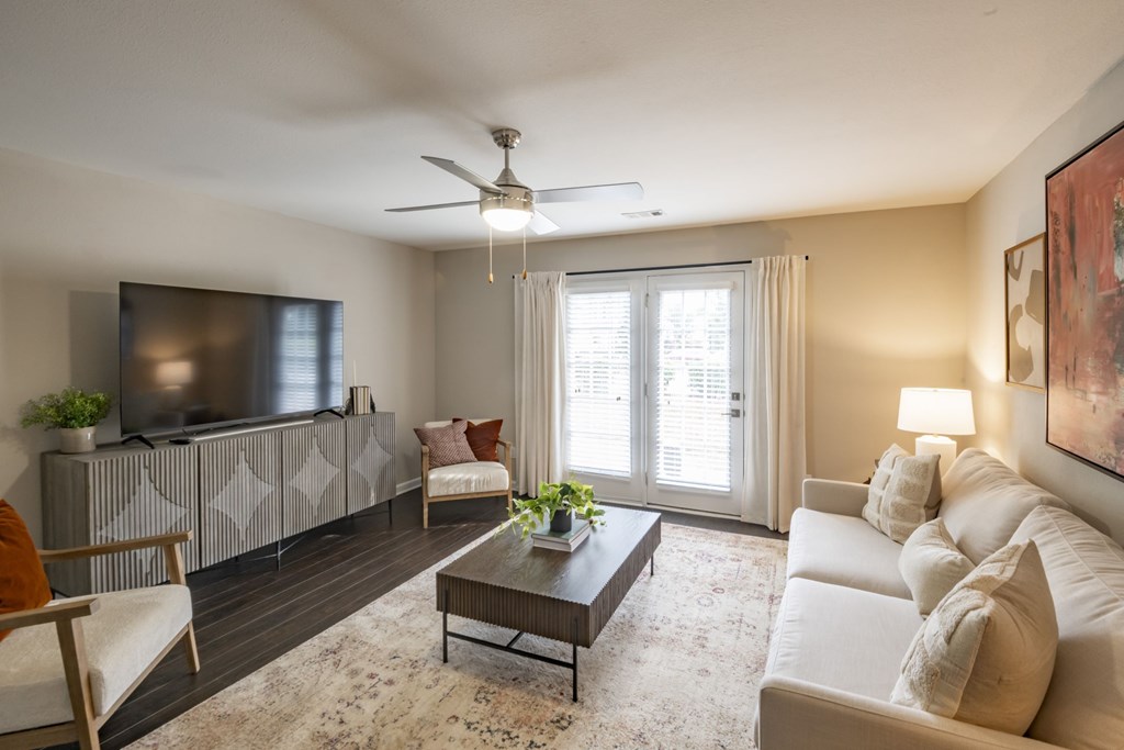 A living room with a television, a couch, a chair, a table, and a plant at Ansley at Town Center Apartments, Georgia