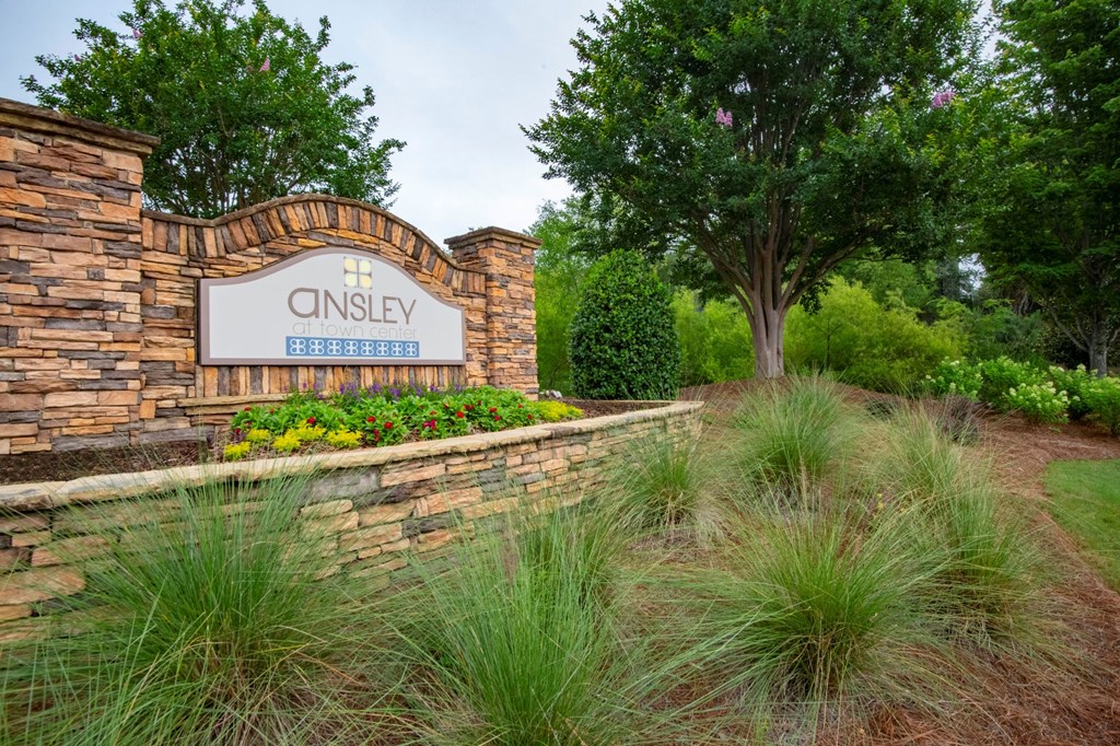 A stone wall with a sign that says Cinsley at Ansley at Town Center Apartments, Evans, GA 30809