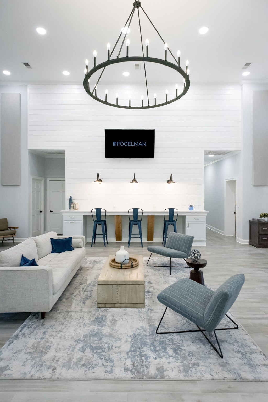 a large open living room with a white wall and a large chandelier