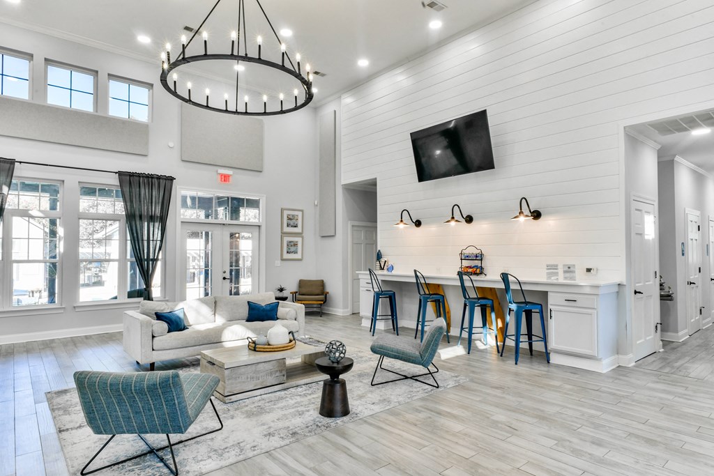 a living room with a couch and a kitchen with a bar and a television