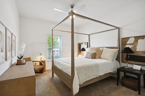 A bedroom with a four poster bed and a table with a lamp on it at Arcadia Cartersville Apartments, Georgia