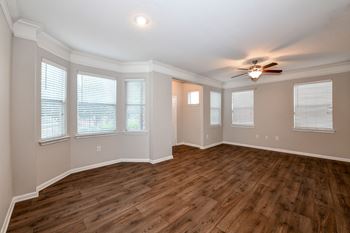 an empty living room with a ceiling fan and windows at Artesian on Westheimer, Houston, Texas