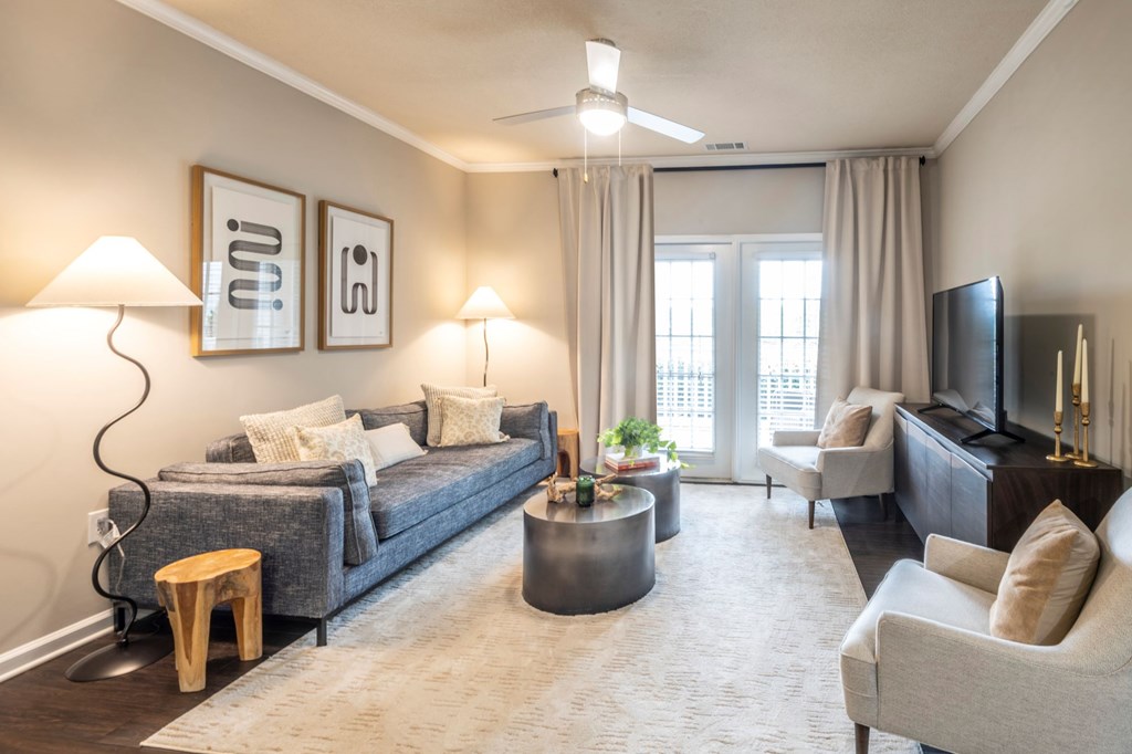 A living room with a grey couch, a round coffee table, and a flat screen TV.