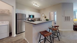 a kitchen with a breakfast bar and stools next to a washer and dryer - Photo Gallery 2