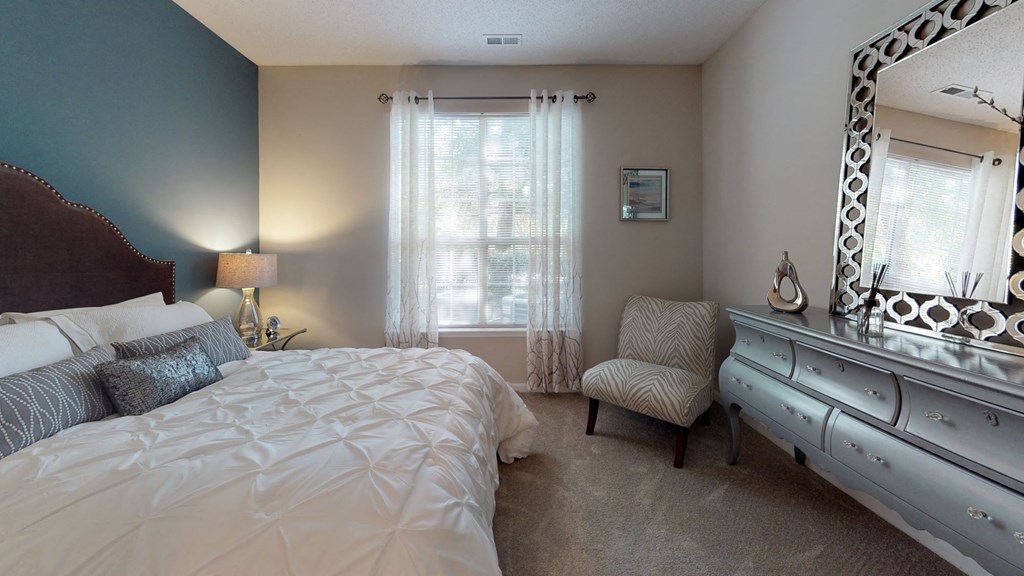 a bedroom with a large bed and a dresser with a mirror at Autumn Park Apartments, Charlotte, NC, 28262