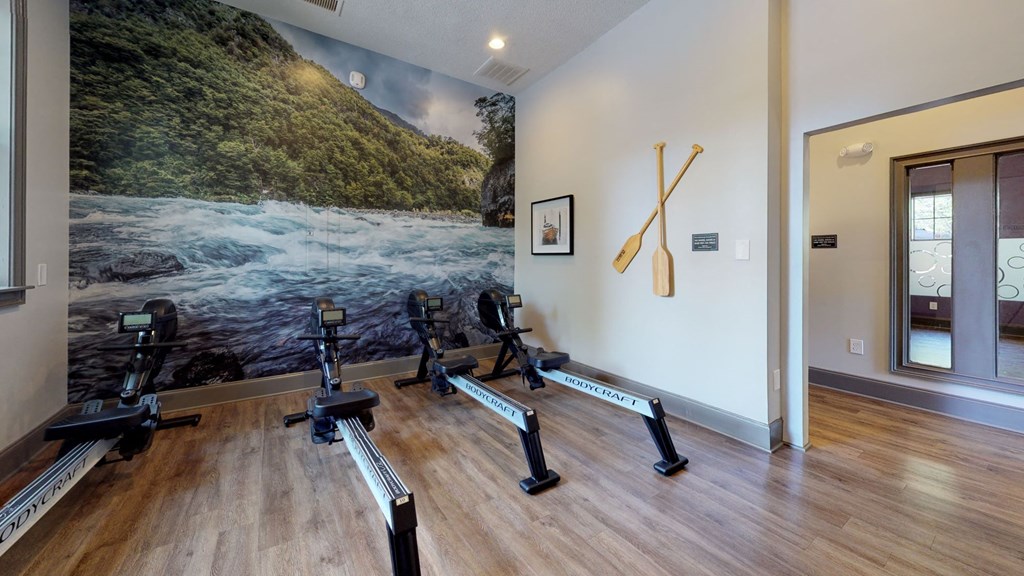 a row of exercise bikes in a room with a large painting on the wall at Autumn Park Apartments, Charlotte, NC