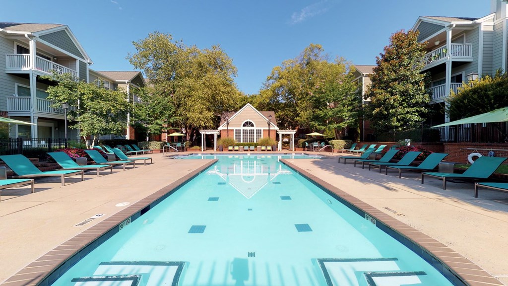 a swimming pool with blue chaise lounge chairs and a house in the background  at Autumn Park Apartments, Charlotte, North Carolina
