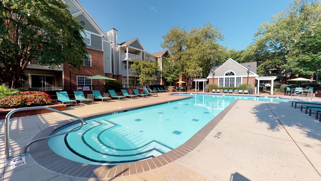a swimming pool with lounge chairs and umbrellas in front of a brick building at Autumn Park Apartments, North Carolina