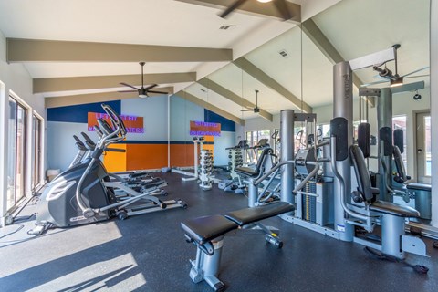 A gym with a variety of equipment including treadmills, weights, and a bench. at Brightwaters Apartments, Little Rock, Arkansas