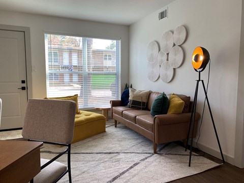 A living room with a yellow chair and a brown couch.