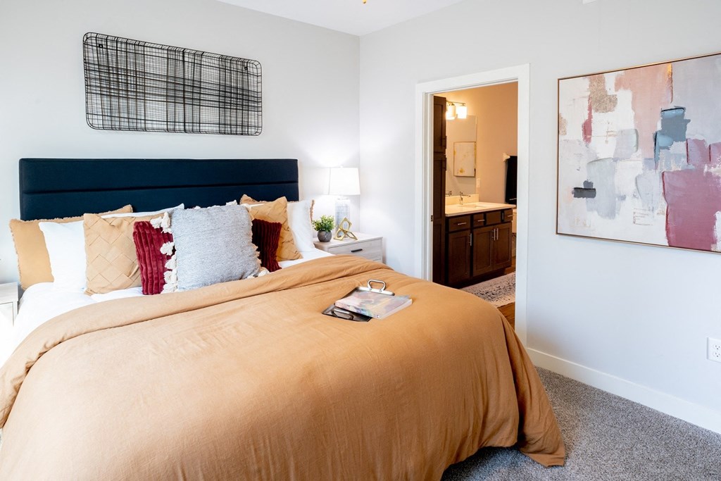 a bedroom with a large bed and a bathroom in the background