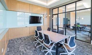 a conference room with a table and chairs and a tv on the wall - Photo Gallery 5