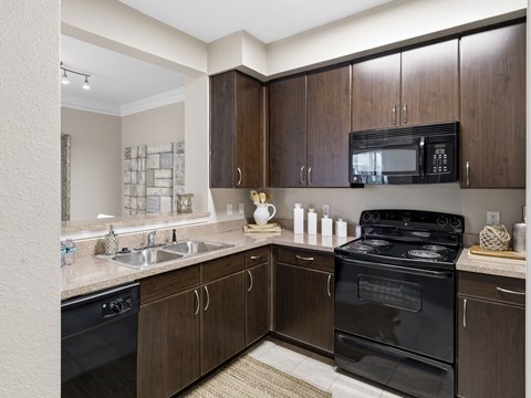 A kitchen with brown cabinets and black appliances.