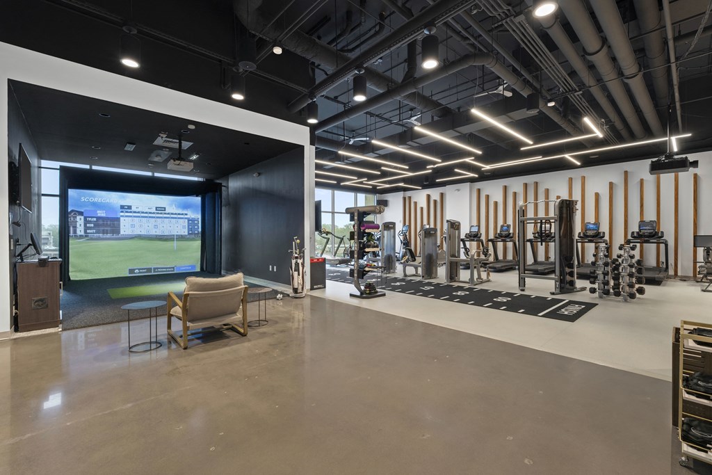 a gym with a large screen on the wall and exercise equipment at Deca Apartments, South Carolina