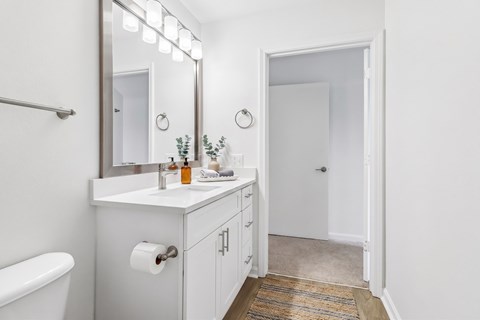 A white bathroom with a mirror, sink, and a white bathtub.