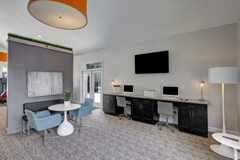 A modern office space with a grey carpet, a white table, and a TV mounted on the wall. at Dunwoody Glen, Atlanta, GA
