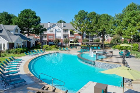 A large swimming pool with a waterfall and lounge chairs.