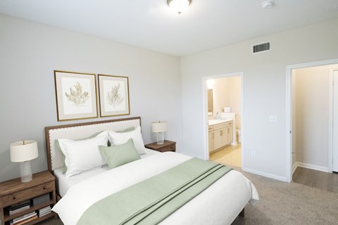 A bedroom with a large bed and two framed pictures above it.