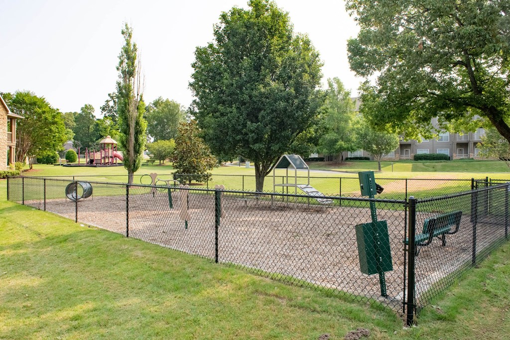 a fenced in dog park with a playground in the background at Appling Lakes, Cordova, TN, 38016
