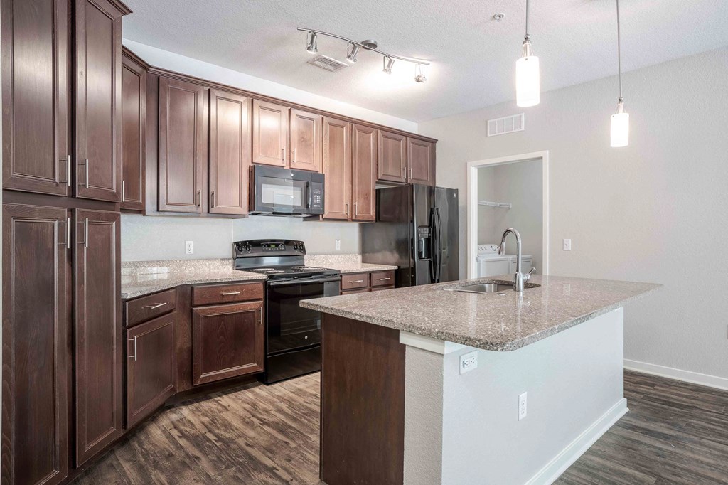 A kitchen with brown cabinets and a granite countertop. A kitchen with brown cabinets and a granite countertop at Park Place Oviedo Apartments, Oviedo
