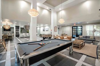 A pool table is in the middle of a room with a black and white checkered floor at Park Place Oviedo Apartments, Oviedo
