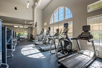 A gym with treadmills, elliptical machines, and other exercise equipment at Park Place Oviedo Apartments, Florida