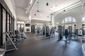 A spacious gym with a variety of equipment and a large window at Park Place Oviedo Apartments, Florida, 32765