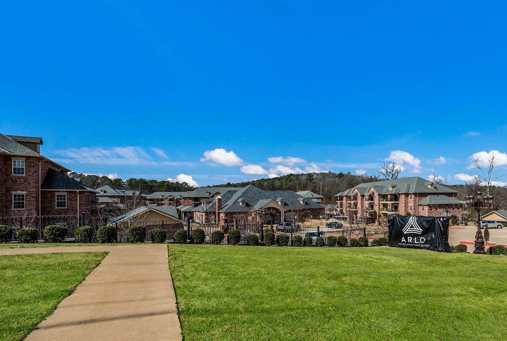 a sidewalk leading to a row of apartments on a green field at Arlo Luxury homes Apartments, Little Rock