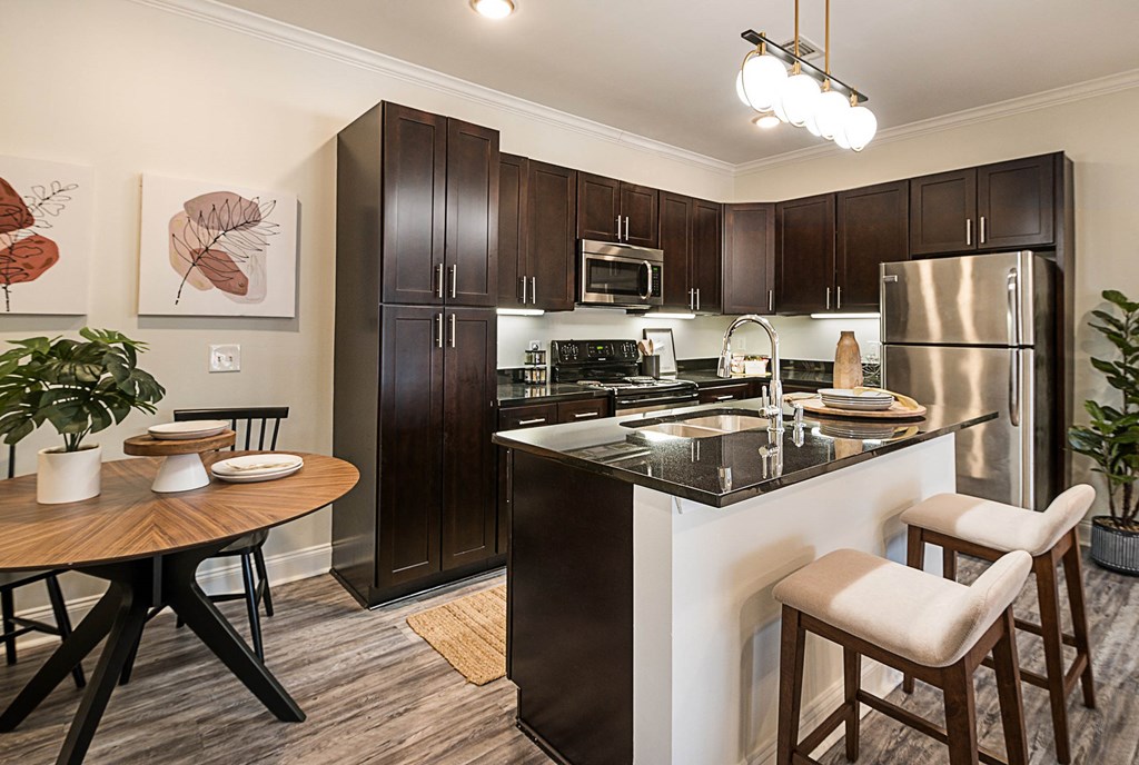 spacious kitchen with stainless steel appliances and a breakfast bar with a wooden table and chairs at Arlo Luxury homes Apartments, Little Rock, 72210