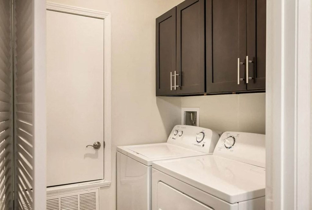 a laundry room with white appliances and dark cabinets  at Arlo Luxury homes Apartments, Arkansas