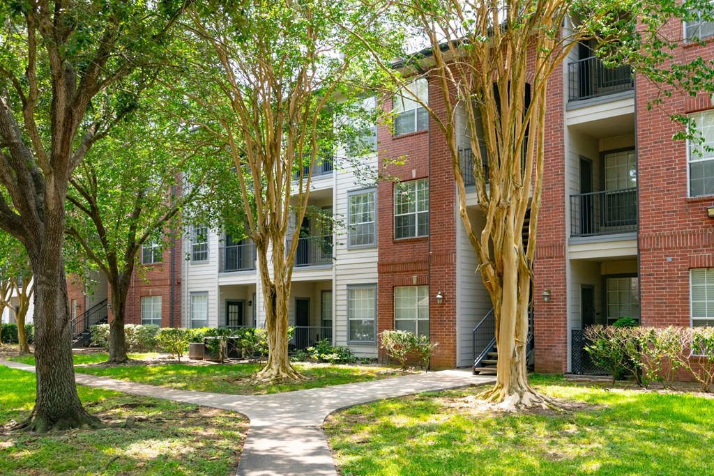 a pathway leads through a grassy area in front of an apartment building  at The Aster Sugar Land, Sugar Land