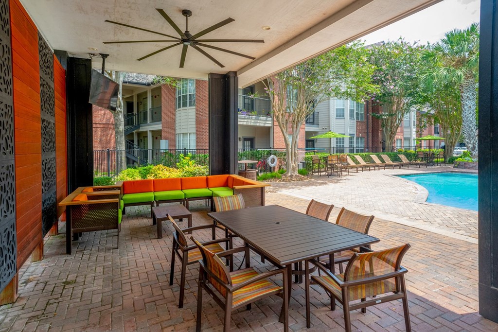 a patio with a wooden table and chairs and a pool in the background  at The Aster Sugar Land, Sugar Land
