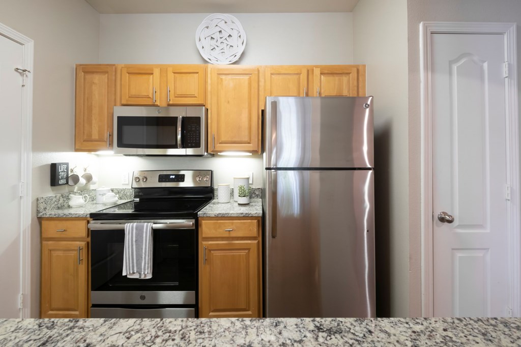 A kitchen with a stainless steel refrigerator, microwave, and oven. at Cambridge Square, Overland Park