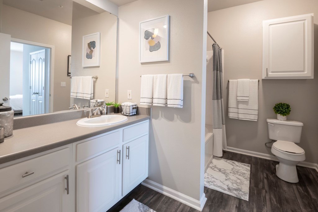 A bathroom with a white toilet, sink, and cabinets. at Cambridge Square, Overland Park, Kansas
