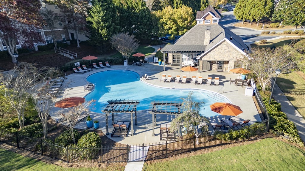 An aerial view of a pool surrounded by trees and a building.
