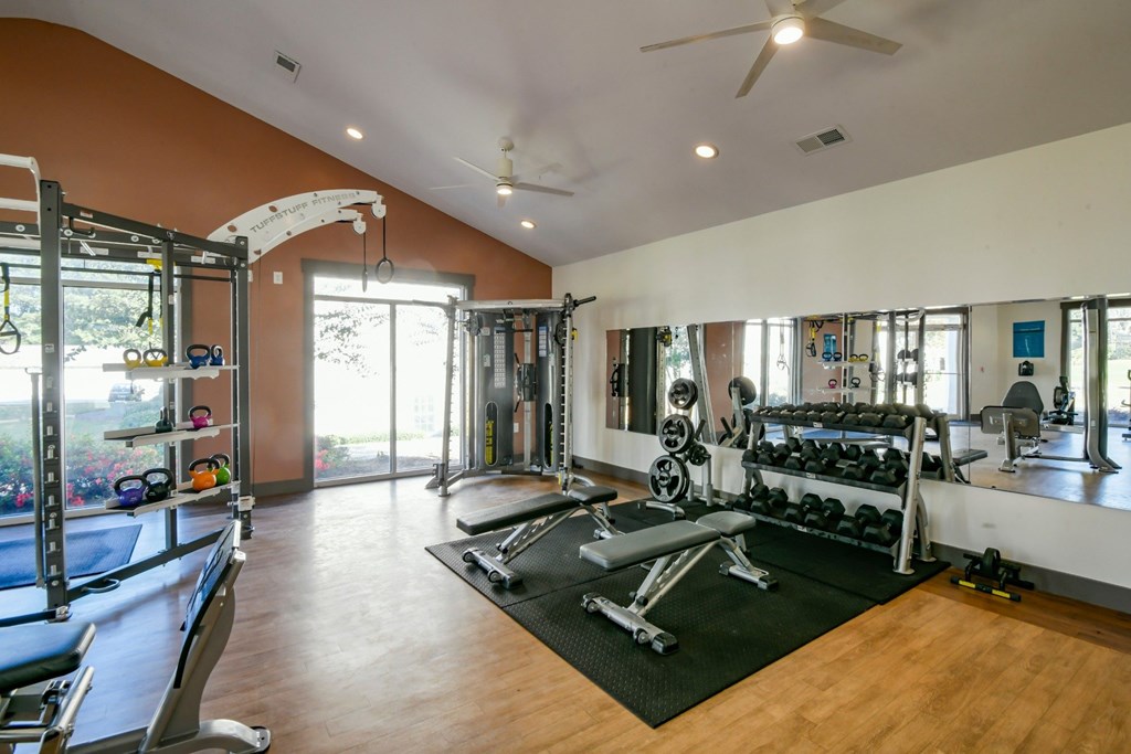 A gym with a variety of equipment including a bench press, a squat rack, and a pull up bar.
