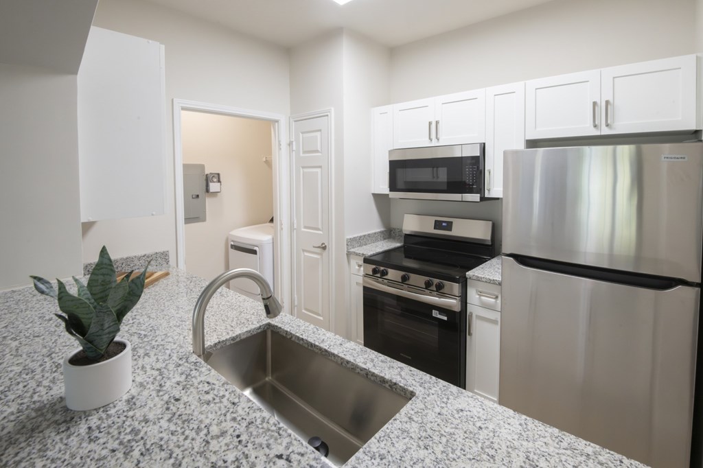 A kitchen with a granite countertop and stainless steel appliances.