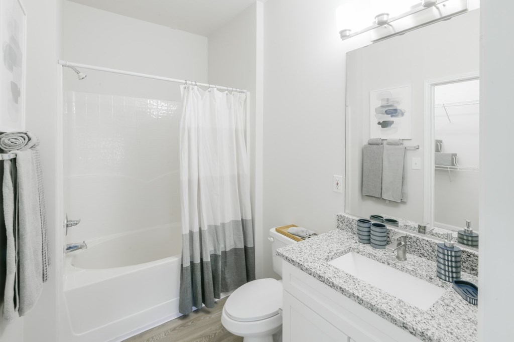 A white bathroom with a toilet, sink, and shower.