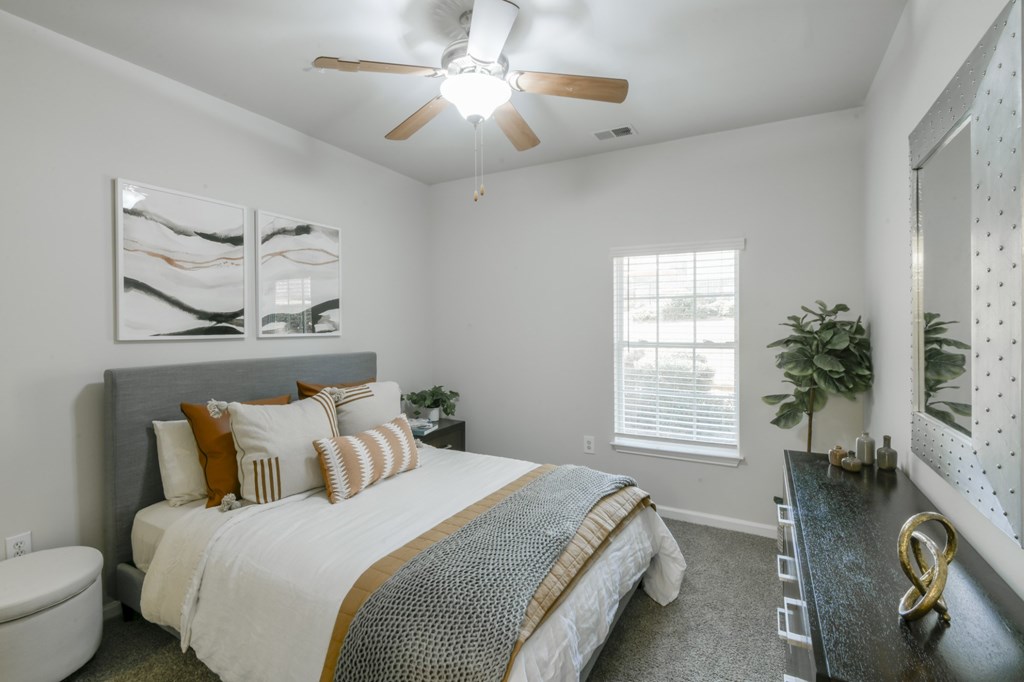 A bedroom with a bed, a ceiling fan, and a window.