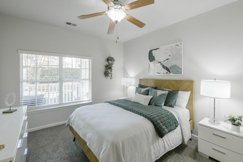 A bedroom with a bed, nightstand, and a ceiling fan.