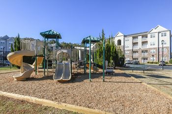 A playground with a slide, swings, and a seesaw.