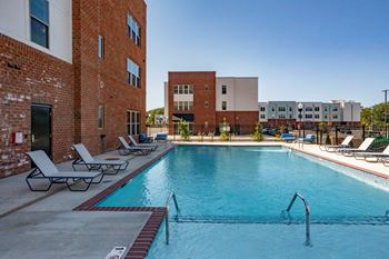 A pool surrounded by chairs and buildings.