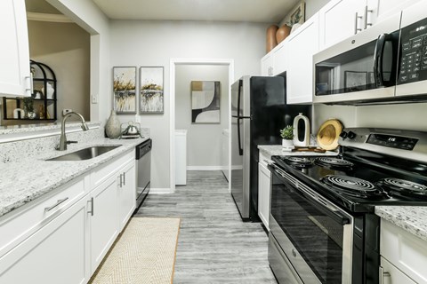A modern kitchen with black and white appliances and a grey floor.