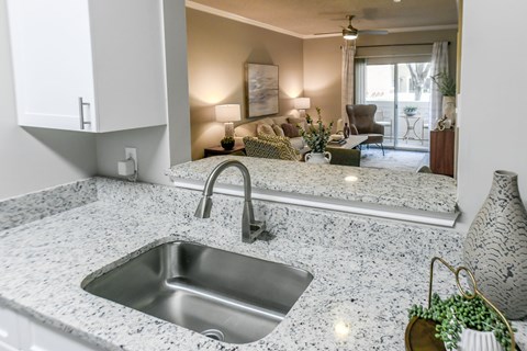 A modern kitchen with a granite countertop and a stainless steel sink.