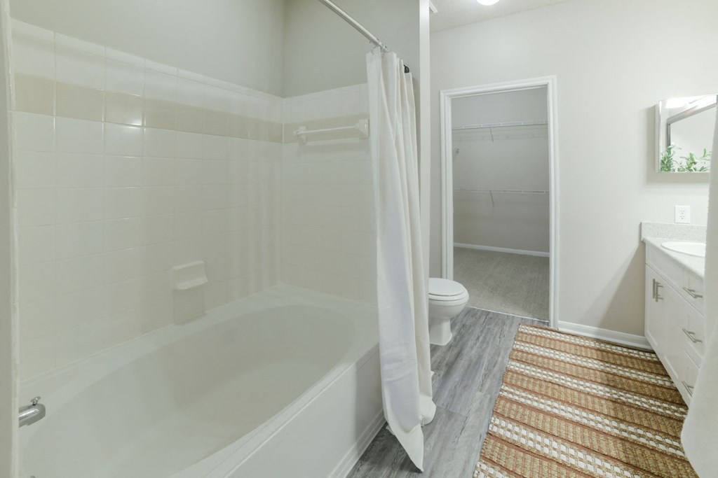 A white bathroom with a tub, toilet, and sink. at Madison Shelby Farms, Memphis